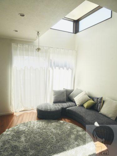 半吹き抜けのあるリビングにソファーとラグがある