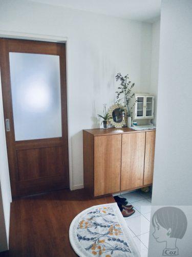 木目の窓付き扉と、木目の靴箱がある玄関ホール