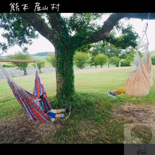 UBUYAMA　PLACE 　樹木に吊るされた２つのハンモックで揺られるこどもたち。芝生と山々に囲まれながら。