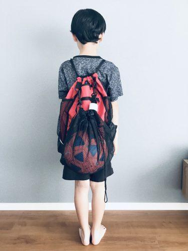 ナップザック型のサッカーボールバッグを120センチの少年が背負った所の後ろ姿