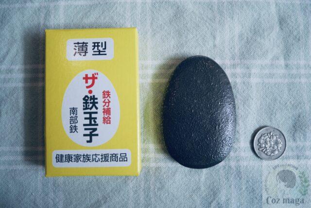 薄型ザ鉄玉子の箱と鉄玉子と百円玉をならべている